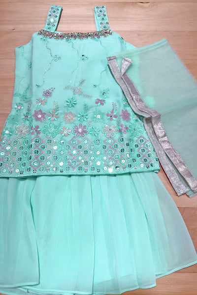sea green girls kurta set outfit with floral embellishments on a wooden surfacesea green girls kurta set outfit with floral embellishments on a wooden surface