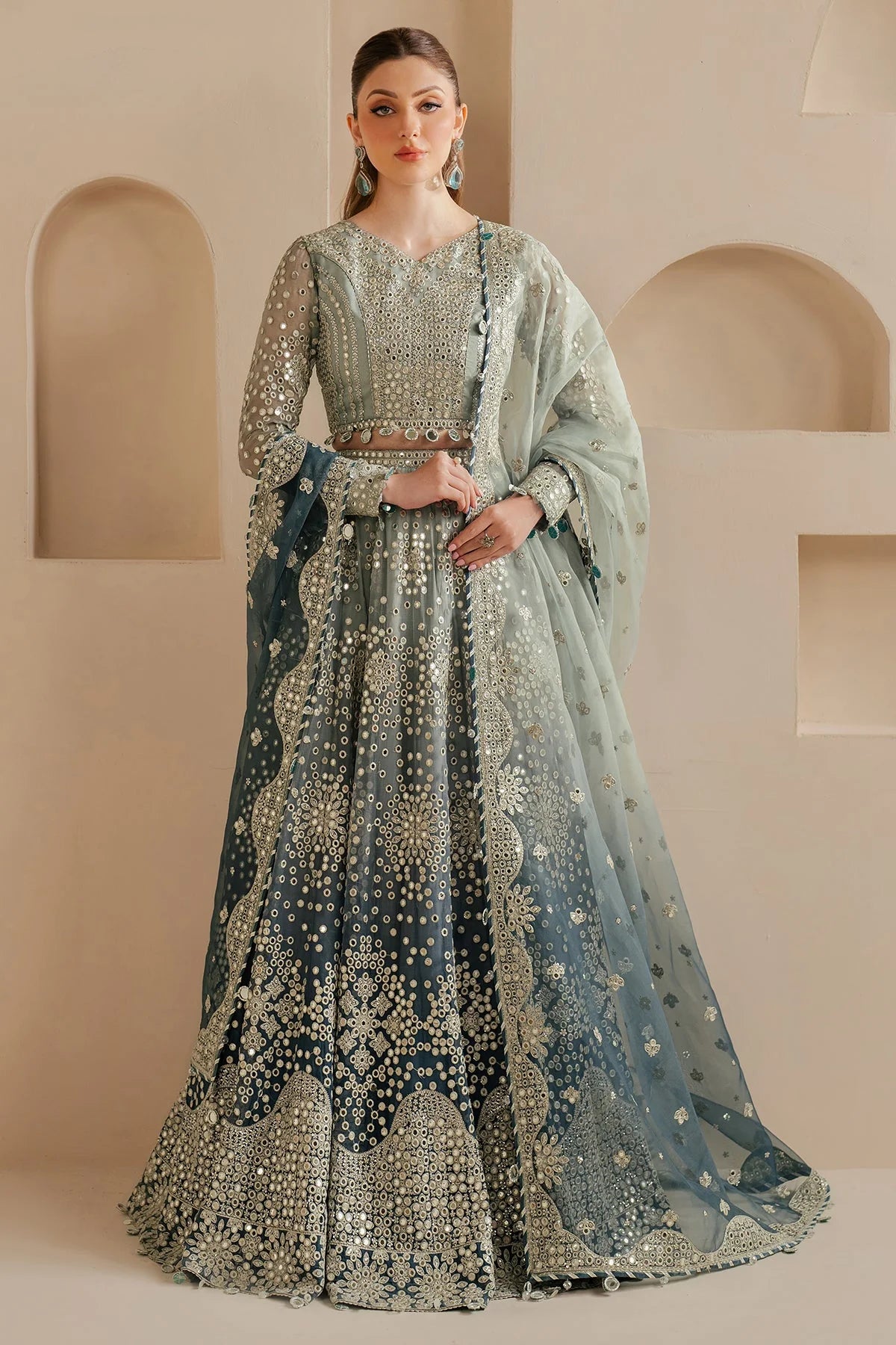 Woman wearing a traditional Lehenga choli outfit with intricate designs in a neutral setting