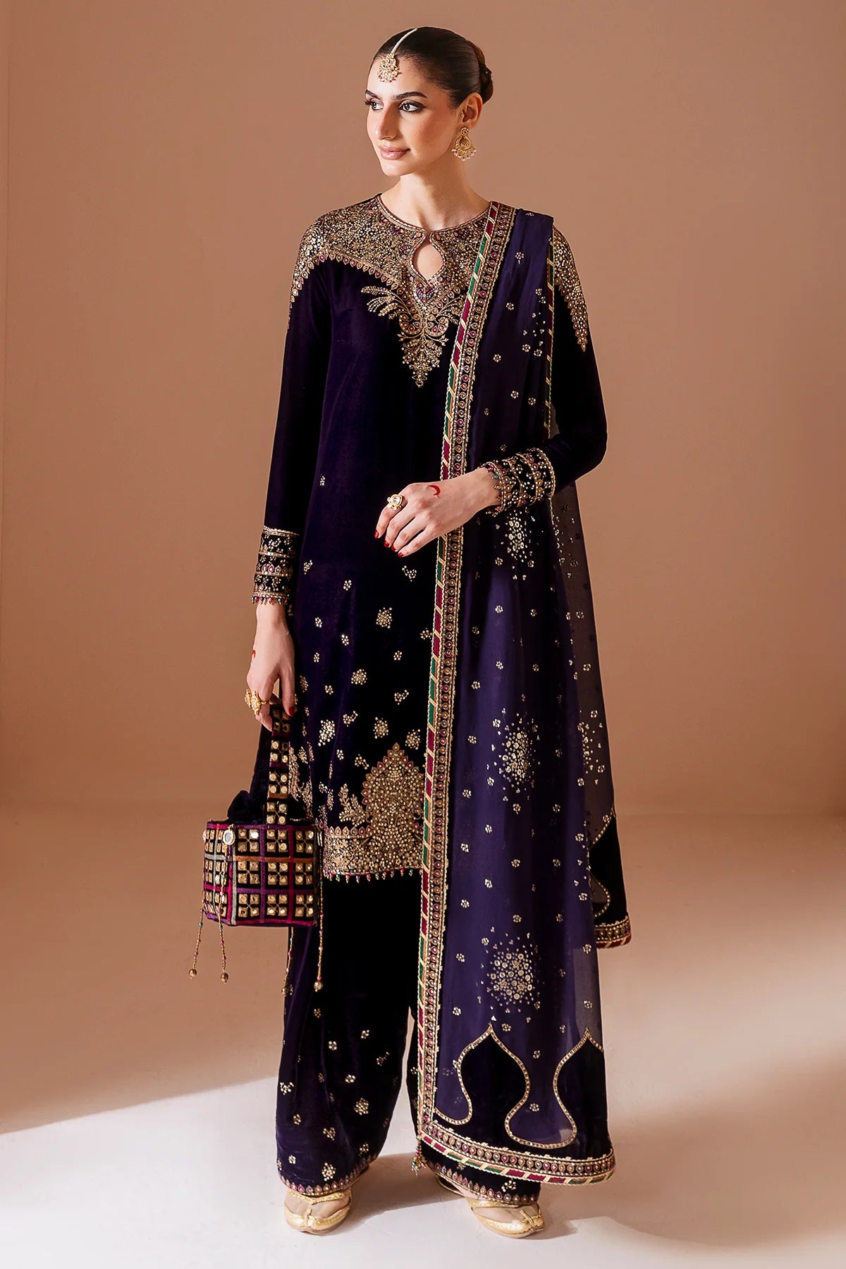 Woman wearing a dark purple embroidered traditional outfit on a beige background
