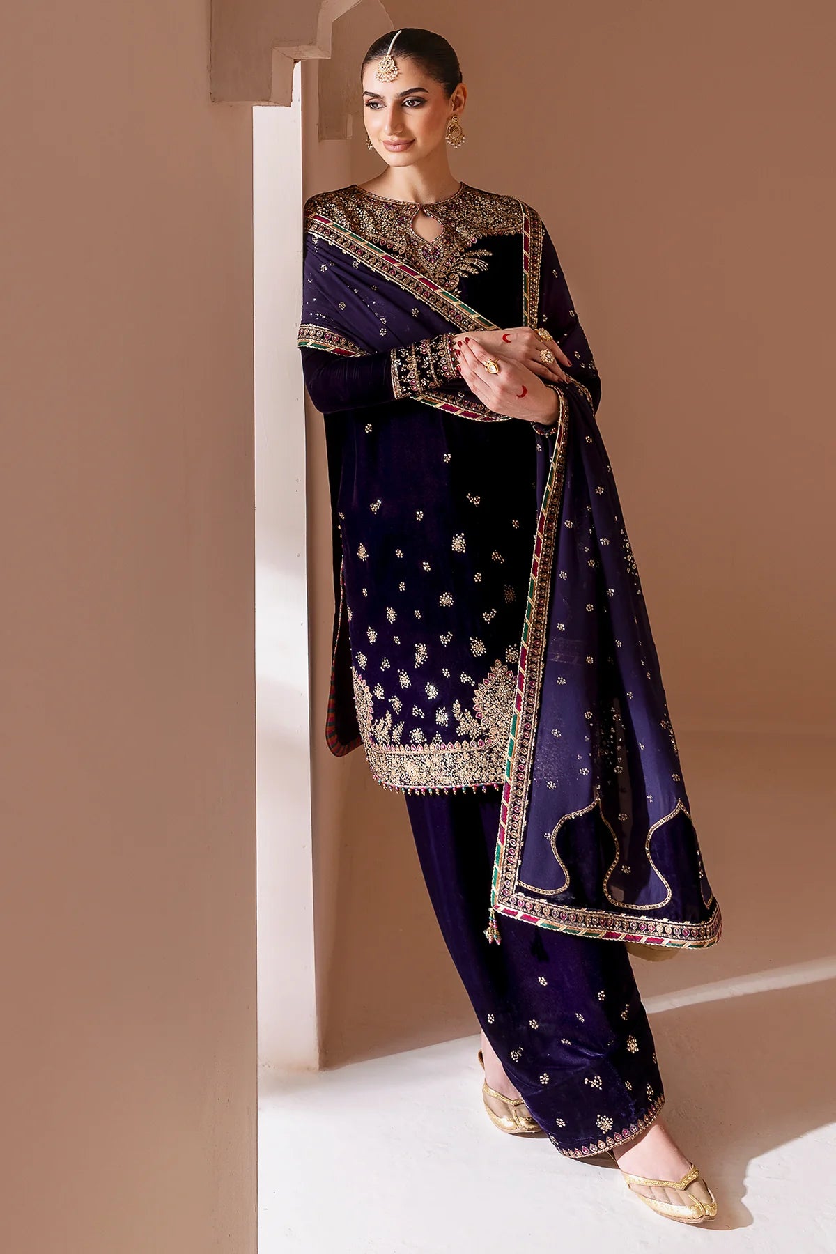 Woman wearing a traditional outfit with intricate designs in a neutral setting