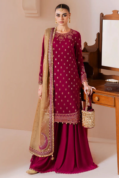 Woman in a maroon traditional velvet sharara outfit with gold embroidery, holding a matching bag, against a neutral background.Woman in a maroon traditional velvet sharara outfit with gold embroidery, holding a matching bag, against a neutral background.