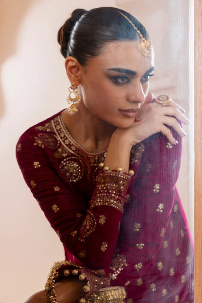 Woman in traditional maroon and gold velvet embroidered outfit with jewelry.Woman in traditional maroon and gold velvet embroidered outfit with jewelry.