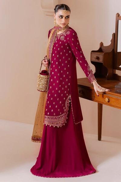 Woman in a traditional maroon velvet sharara outfit with gold details, holding a dupatta, against a neutral background.Woman in a traditional maroon velvet sharara outfit with gold details, holding a dupatta, against a neutral background.