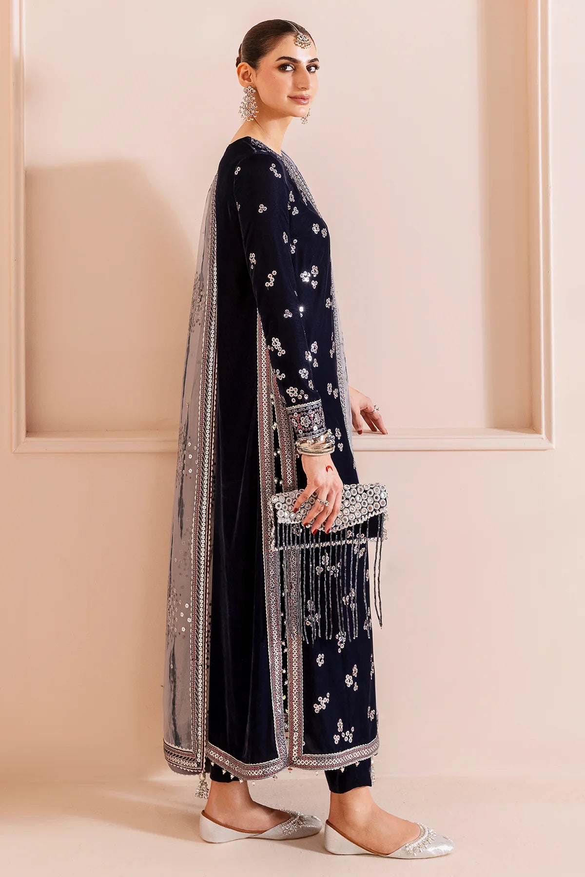 Woman in a navy blue velvet kurta set traditional outfit with silver embroidery in a neutral setting