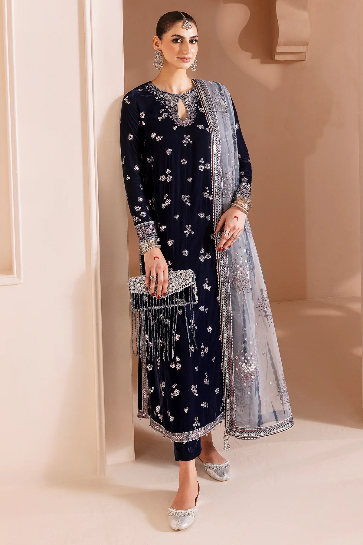Woman in a navy blue velvet kurta set traditional outfit with silver embroidery in a neutral setting