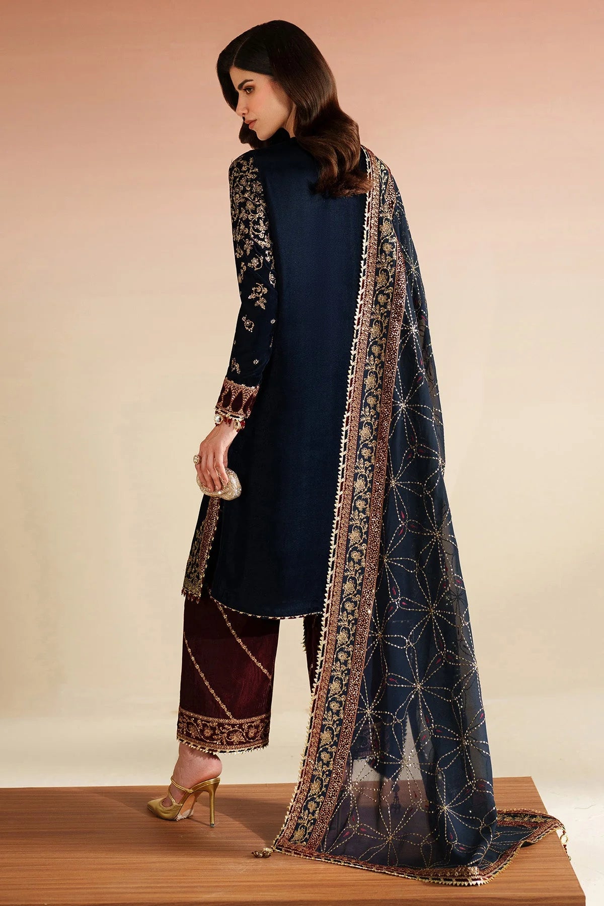 Woman wearing a navy blue outfit with a patterned dupatta on a beige background