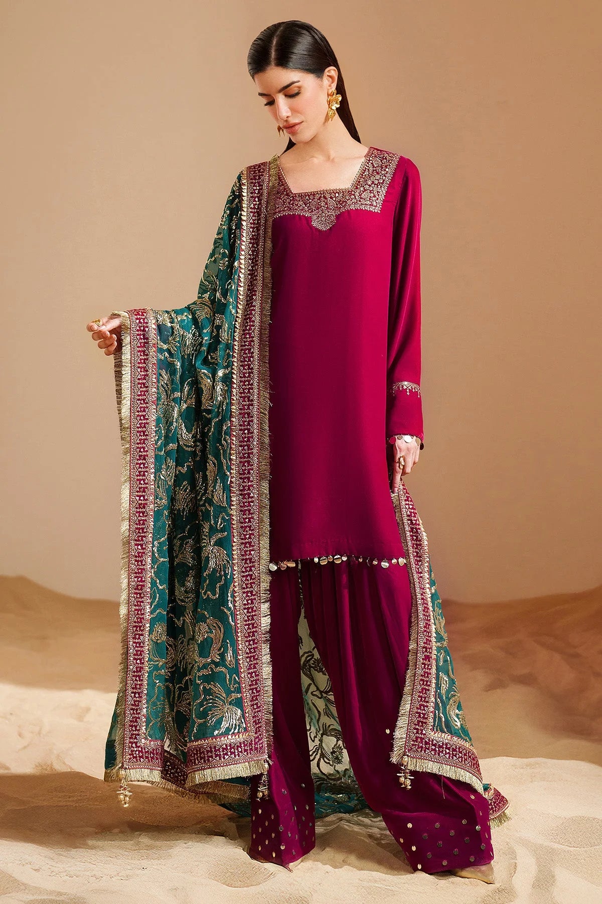Woman wearing a traditional pink velvet kurta salwar outfit with green dupatta against a beige background