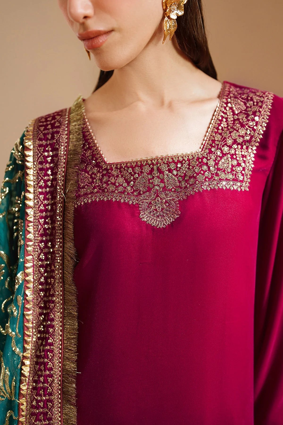Woman wearing a traditional pink velvet kurta salwar outfit with green dupatta against a beige background