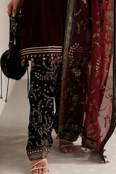 Woman in traditional maroon and navy velvet salwar suit outfit with a matching dupatta in a minimalistic setting.Woman in traditional maroon and navy velvet salwar suit outfit with a matching dupatta in a minimalistic setting.