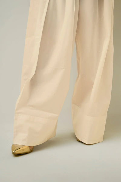 Beige farshi shalwar pants with gold shoes on a neutral backgroundBeige farshi shalwar pants with gold shoes on a neutral background