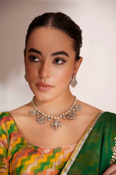 Woman wearing a green saree with a colorful blouse, Gold Kundan Polki Necklace Set with Pearl Strand Dual Tone Finish against a plain background