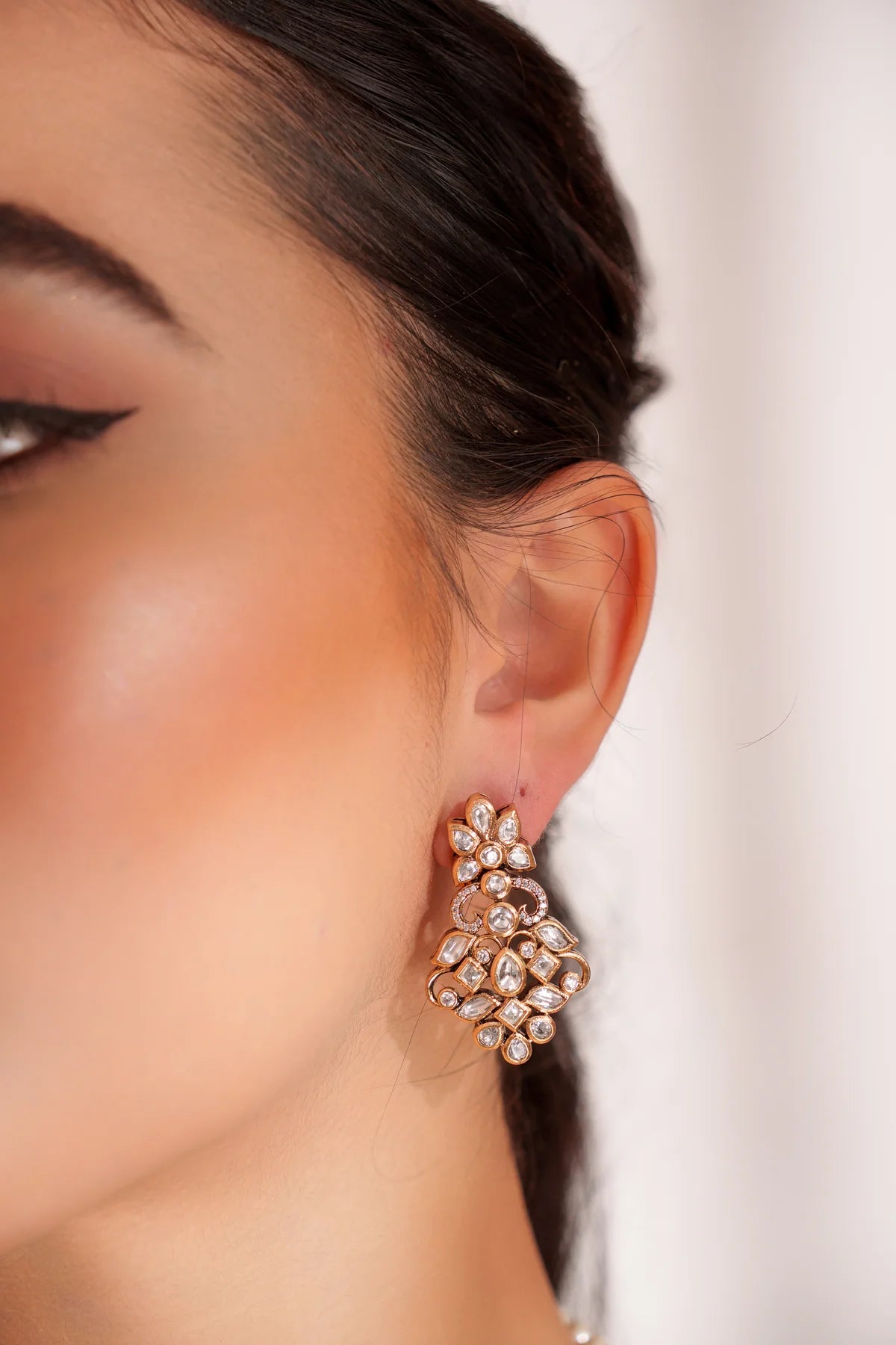 Close-up of a woman wearing a sparkling kundan earring with a blurred background