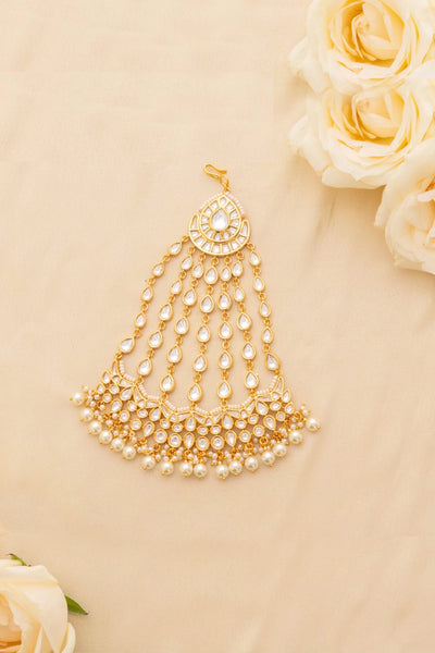 Gold kundan passa headpiece with pearls on a beige background with white roses