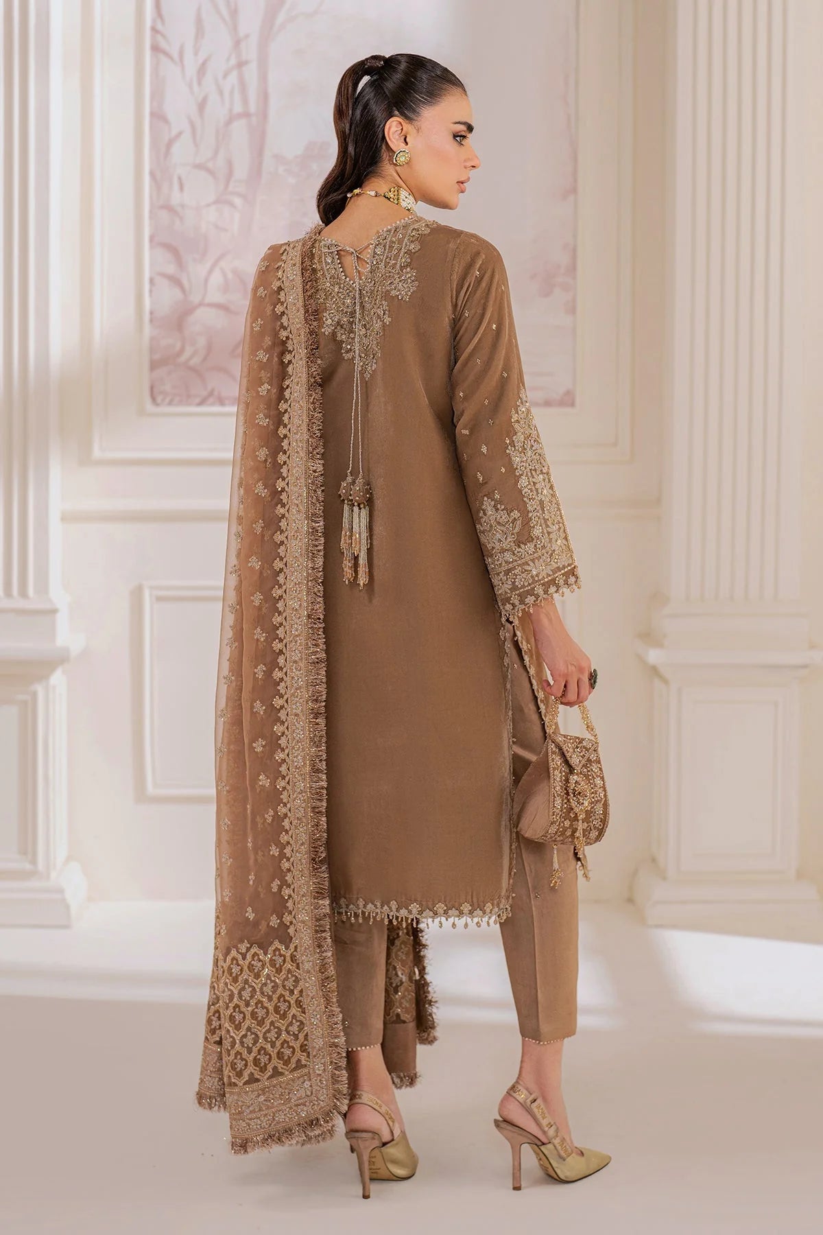 Woman wearing a beige velvet salwar suit embroidered outfit in a minimalistic setting