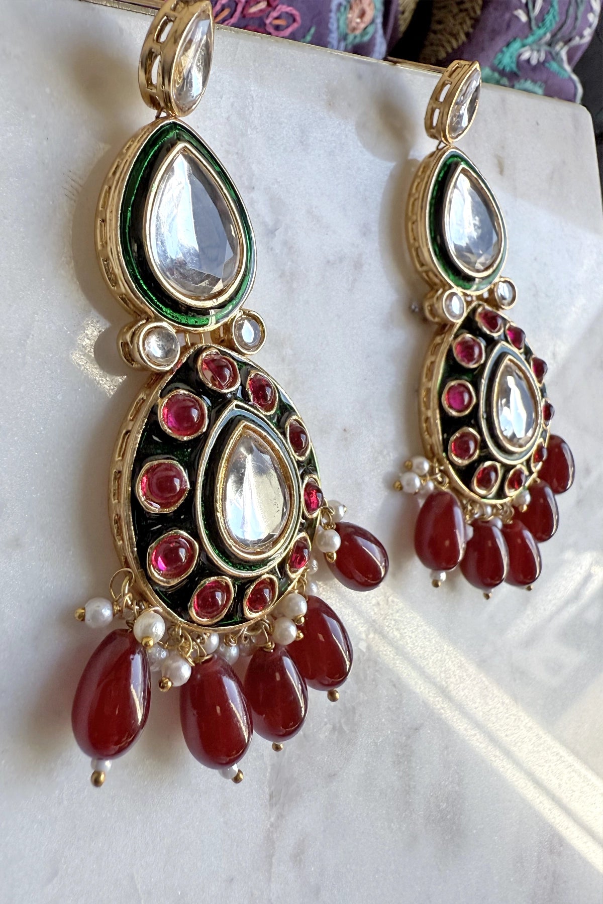 Ornate earrings with red stones and gold accents on a white surface