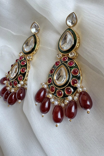 Ornate earrings with red stones and gold accents on a white fabric backgroundOrnate earrings with red stones and gold accents on a white fabric background
