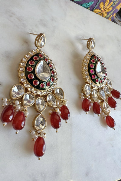 Pair of ornate earrings with red stones and gold accents on a marble surfacePair of ornate earrings with red stones and gold accents on a marble surface