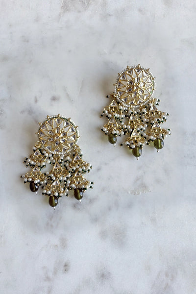 Pair of gold and green earrings on a marble surface