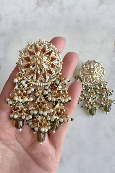 Gold and pearl earrings held in a hand on a light marble backgroundGold and pearl earrings held in a hand on a light marble background