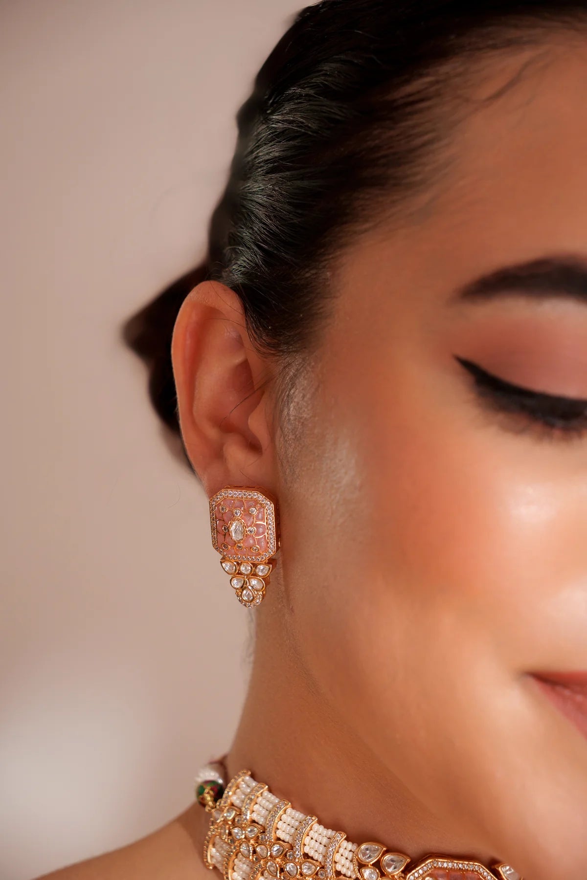 Close-up of a women wearing a traditional Peach Pink Kundan Choker Set against a neutral background