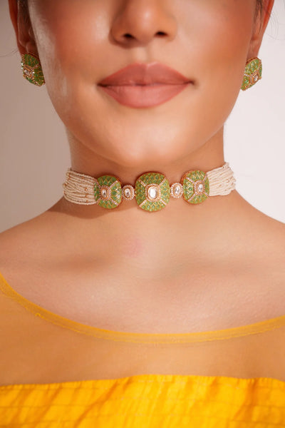Close-up of a women wearing a Gold Finish Green Stones Kundan Polki Necklace And Earring Set with a yellow top.