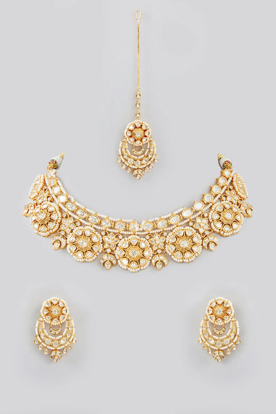 Gold kundan necklace and earrings set on a gray backgroundGold kundan necklace and earrings set on a gray background
