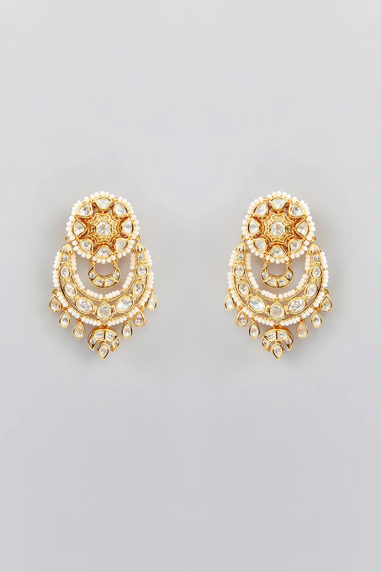 Pair of gold kundan earrings with intricate designs on a light gray background