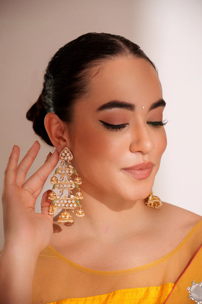 Woman wearing gold kundan earrings with a neutral background