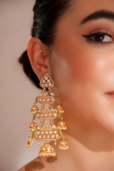 Close-up of a woman wearing an ornate gold and green kundan earring against a neutral backgroundClose-up of a woman wearing an ornate gold and green kundan earring against a neutral background