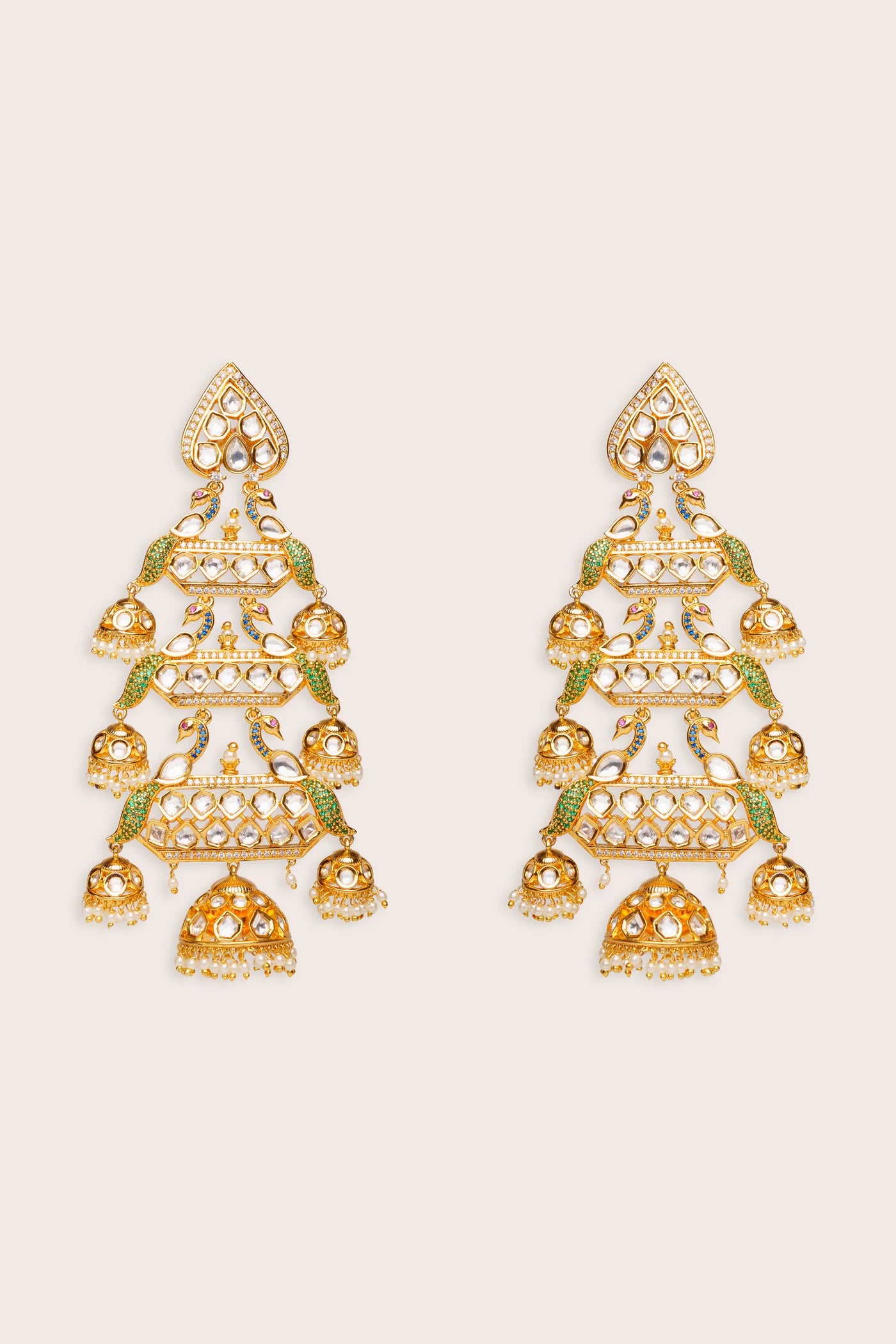 Pair of gold and green kundan earrings on a beige background
