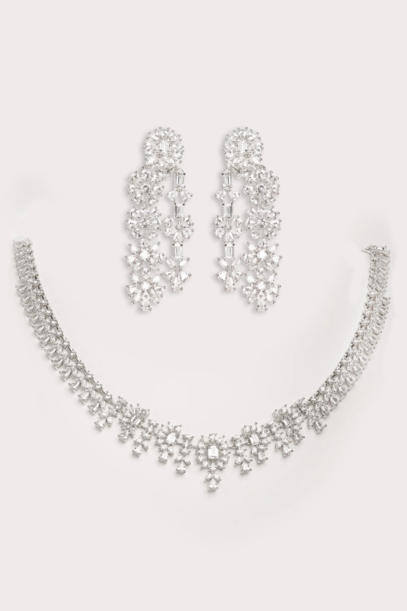 Silver necklace and earrings set on a light gray background