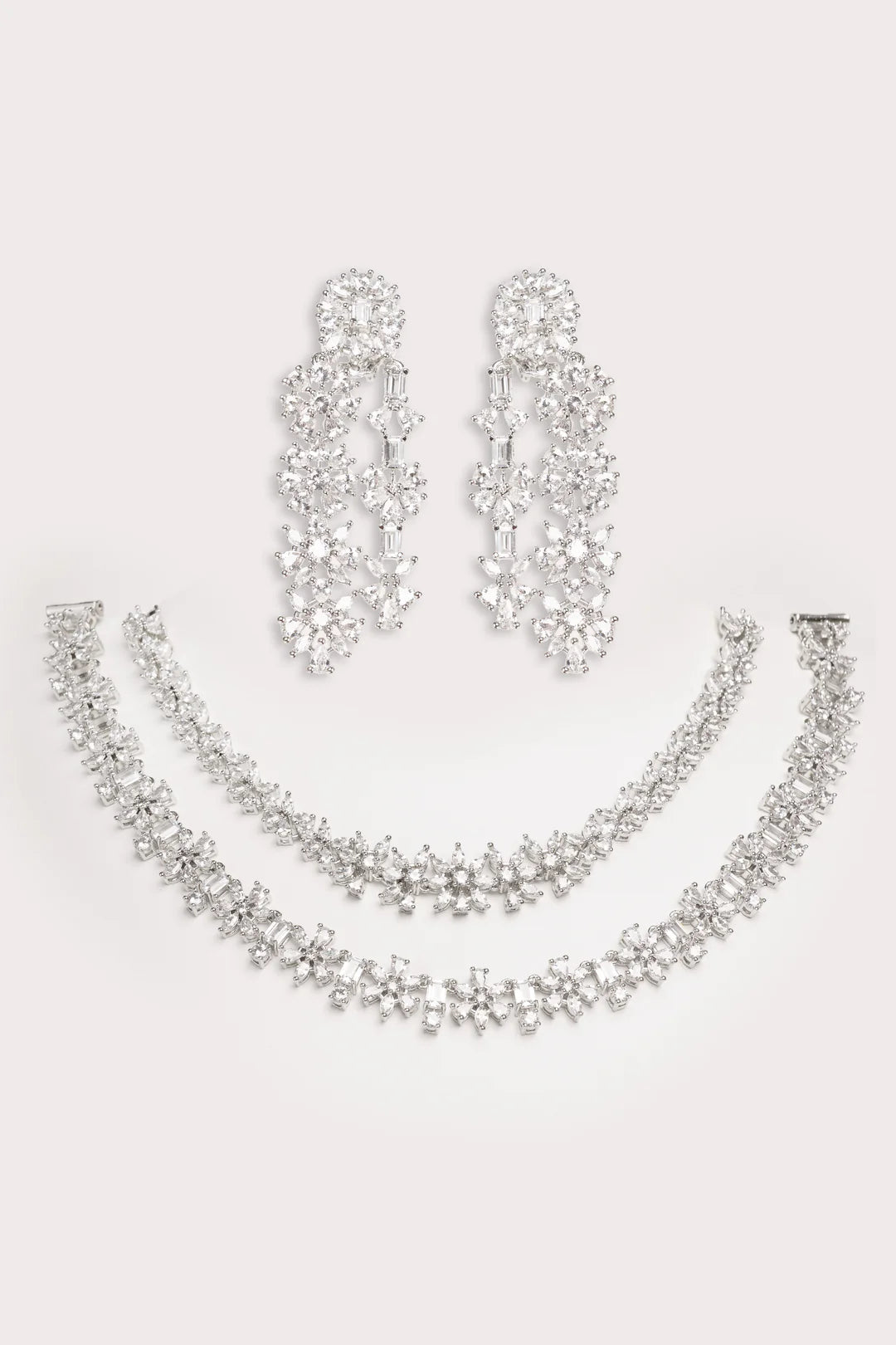 Silver necklace and earrings set on a light gray background