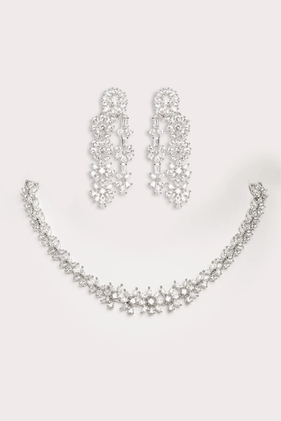 Silver necklace and earrings set on a light gray background