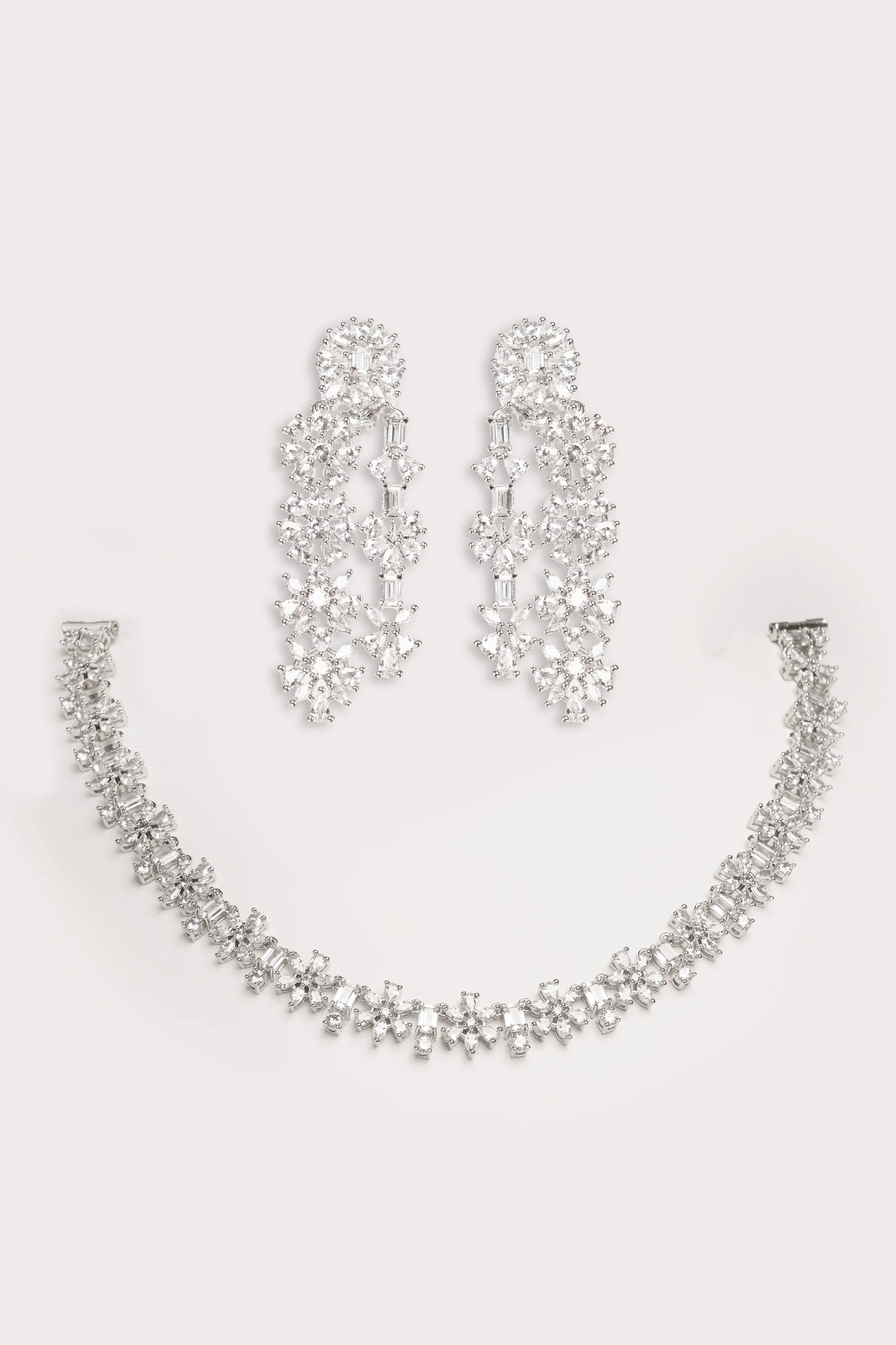 Silver necklace and earrings set on a light gray background