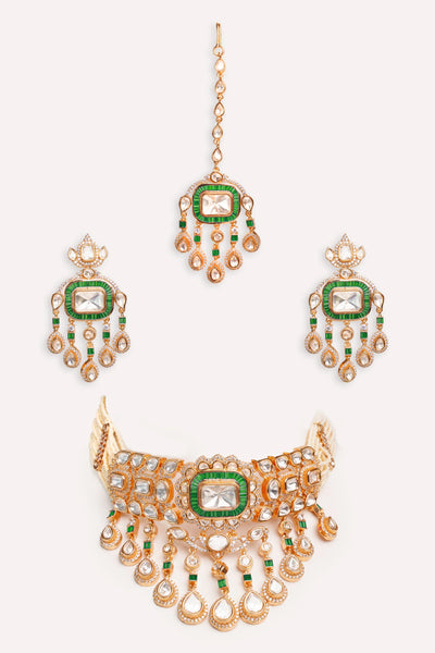 Gold Kundan necklace and earrings with green gemstones on a white backgroundGold Kundan necklace and earrings with green gemstones on a white background