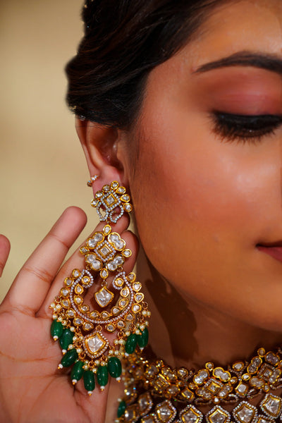 Close-up of a person wearing elaborate gold and green earrings with a blurred backgroundClose-up of a person wearing elaborate gold and green earrings with a blurred background