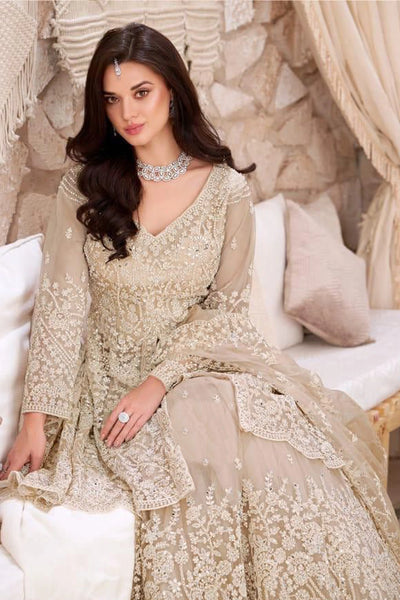 Woman in a beige embroidered lehenga outfit sitting on a decorative couch.Woman in a beige embroidered lehenga outfit sitting on a decorative couch.