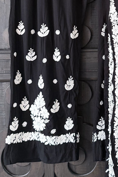 Black dress with white floral embroidery on a wooden backgroundBlack dress with white floral embroidery on a wooden background
