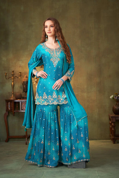 Woman wearing a turquoise embroidered traditional outfit against a neutral backgroundWoman wearing a turquoise embroidered traditional outfit against a neutral background