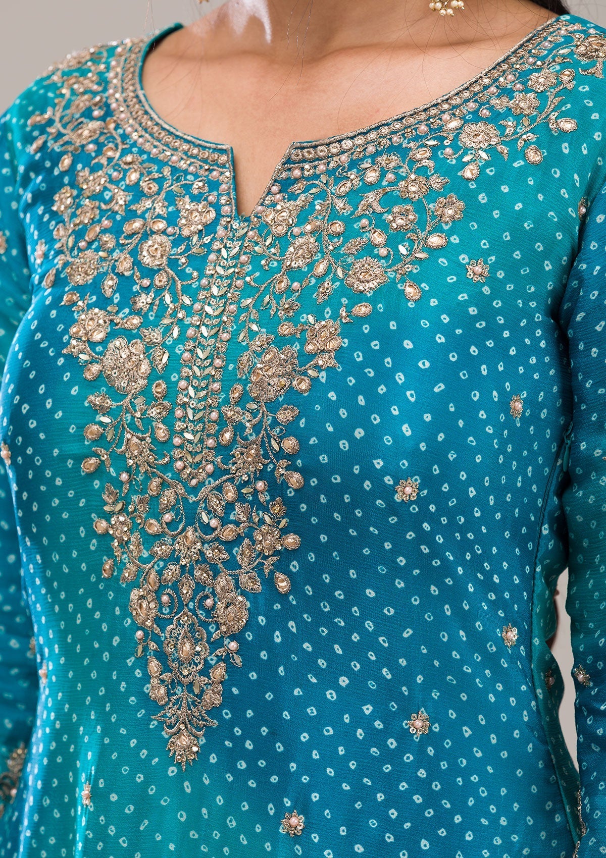 Close-up of a teal embroidered sharara outfit with gold zardosi embroidery
