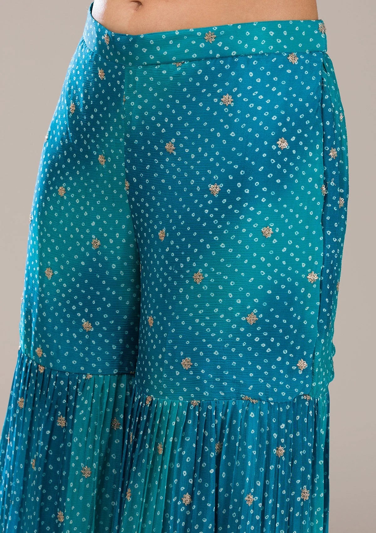 Teal sharara bottom with white bandhani floral pattern on a gray background