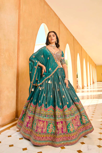 Woman in a traditional green embroidered lehenga set standing in an elegant hallway.