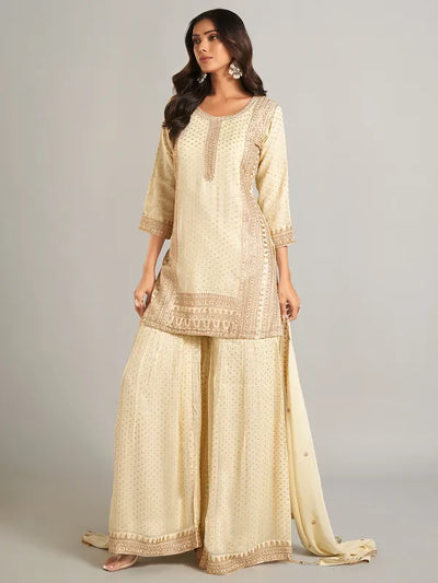 Woman wearing a cream traditional outfit with intricate patterns on a plain backgroundWoman wearing a cream traditional outfit with intricate patterns on a plain background