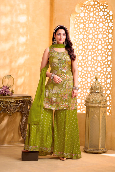 Woman in a Mehendi Green Embroidered Kurta Set standing in a decorated room with a decorative wall and table.