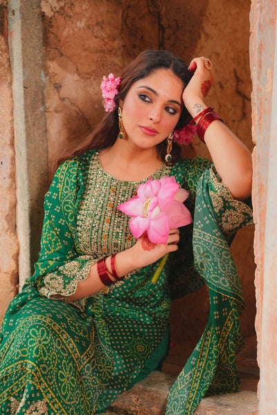Woman in a green traditional outfit holding pink flowers in an outdoor settingWoman in a green traditional outfit holding pink flowers in an outdoor setting