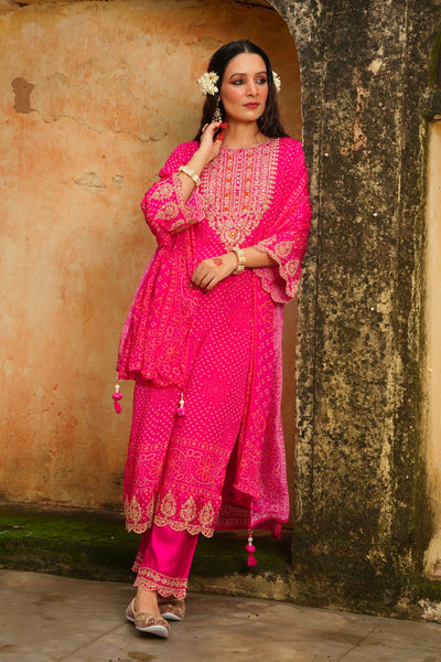 Woman in a bright pink traditional outfit standing against a textured wall.Woman in a bright pink traditional outfit standing against a textured wall.