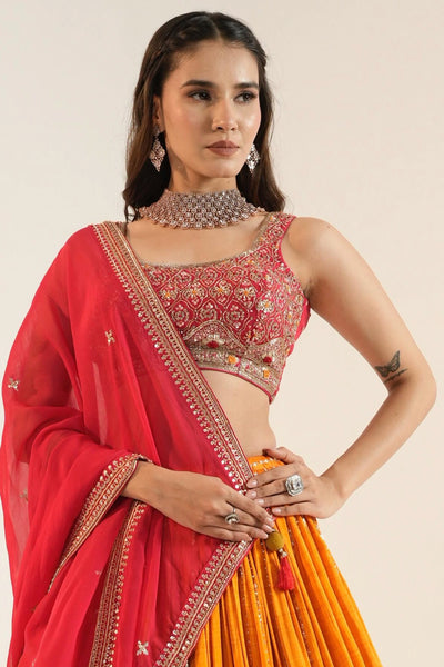 Woman wearing a red and orange lehenga set out with intricate embroidery Woman wearing a red and orange lehenga set out with intricate embroidery 