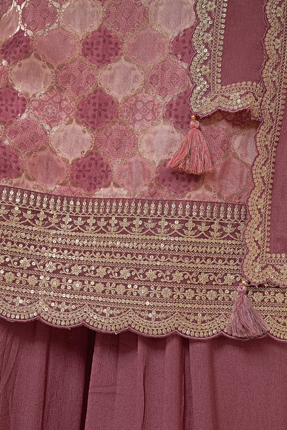 Close-up of a mauve embroidered fabric with gold detailing and tassels.