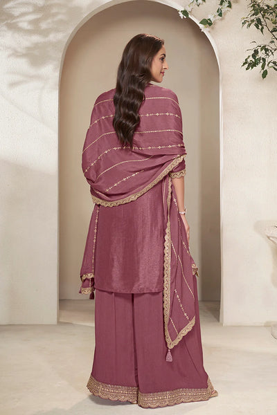 Woman wearing a maroon traditional sharara outfit with gold embroidery in a neutral settingWoman wearing a maroon traditional sharara outfit with gold embroidery in a neutral setting