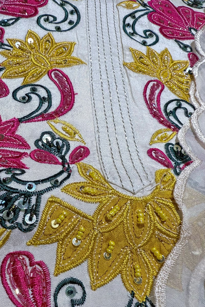 Close-up of embroidered fabric with floral patterns in gold, pink, and black on a white background.Close-up of embroidered fabric with floral patterns in gold, pink, and black on a white background.